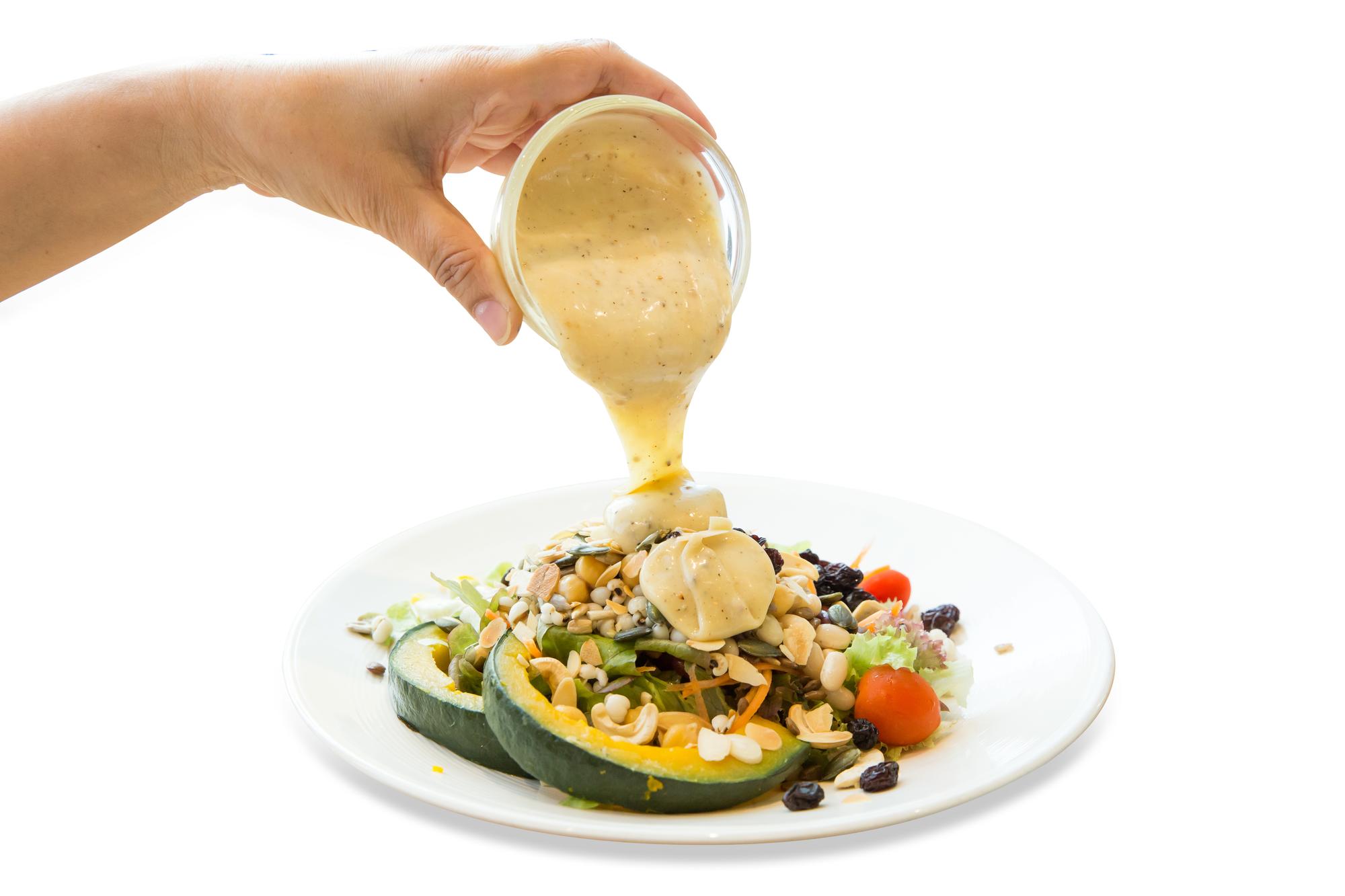 Close-up: hand pouring sauce over protein